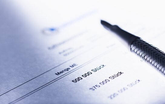 Ein Dokument mit Mengenangaben und einem Stift im Hintergrund.