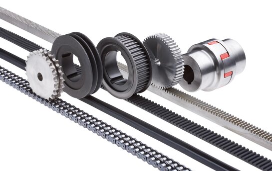 Verschiedene Zahnräder und Riemen aus der Antriebstechnik nebeneinander angeordnet.
