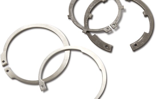 Vier metallische Sicherungselemente in verschiedenen Größen liegen übereinander angeordnet.