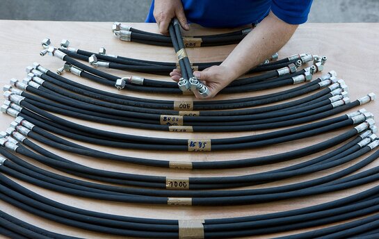 Eine Person arbeitet an einem Tisch mit mehreren schwarzen Schläuchen und Metallanschlüssen.