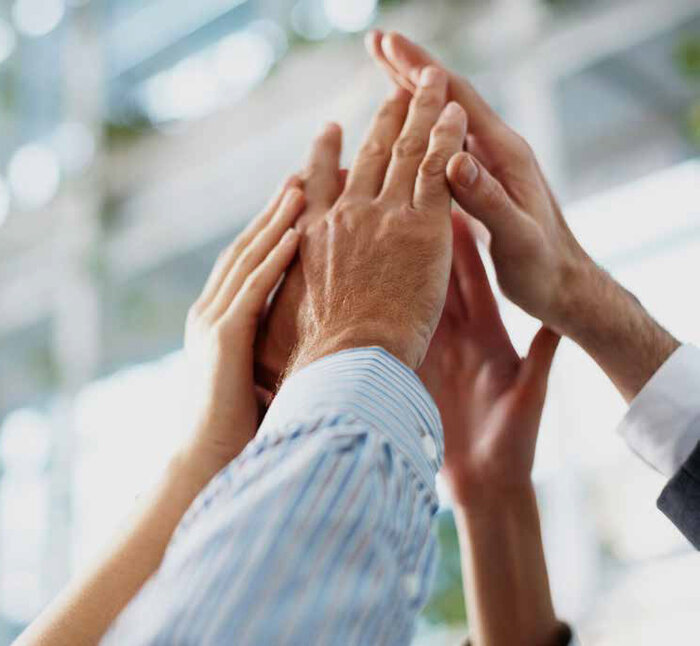 Mehrere Hände treffen sich zu einem High-Five in einem Büro.